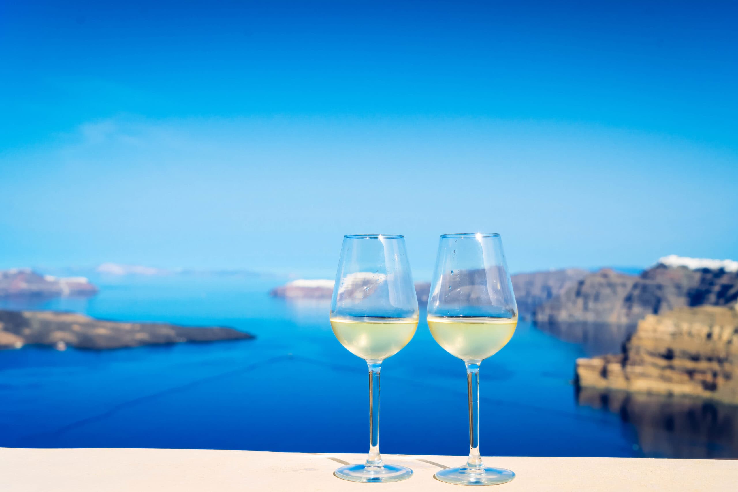 Two,Glasses,Of,White,Wine,With,Aegaen,Sea,In,Background,
