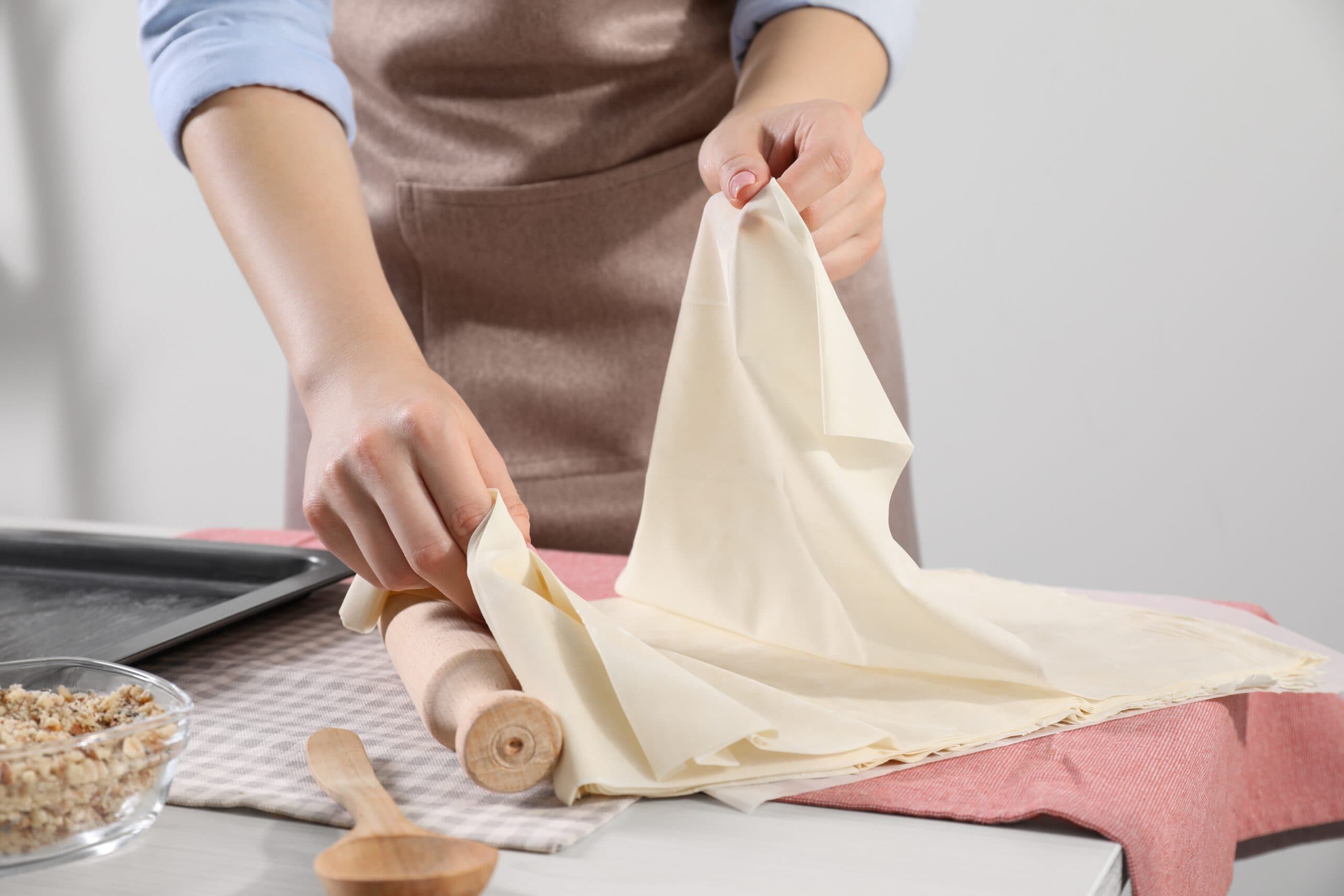 Making,Delicious,Baklava.,Woman,With,Dough,At,White,Table,,Closeup