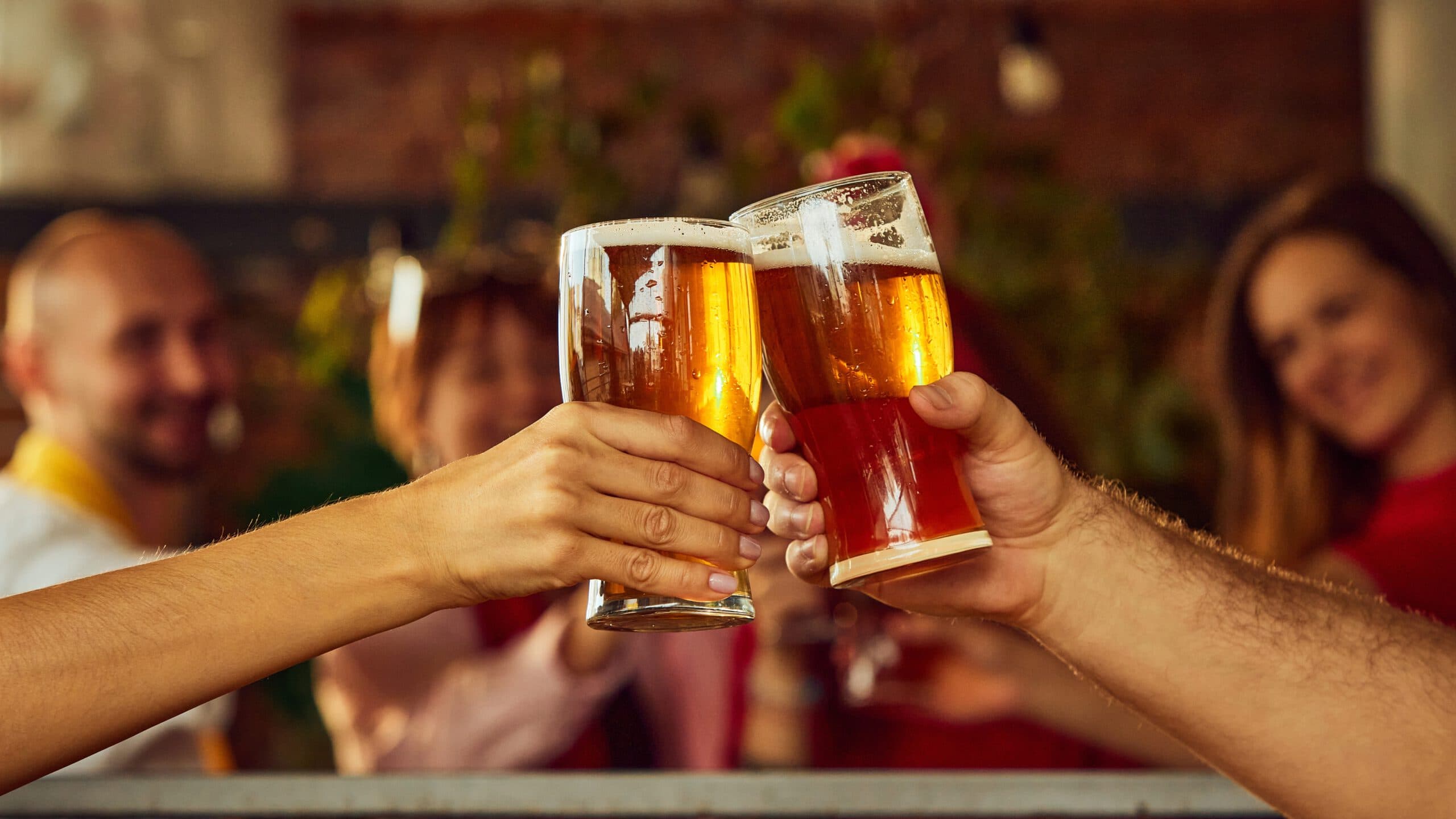 Close-up,Of,Two,Raised,Glasses,Filled,With,Amber,Beer,,With