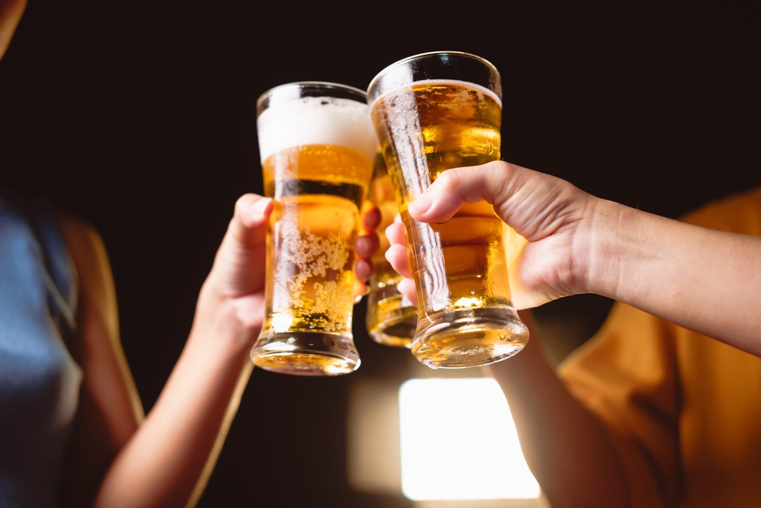 A,Man's,And,Woman's,Hands,Raise,Beer,Glasses,Group,In