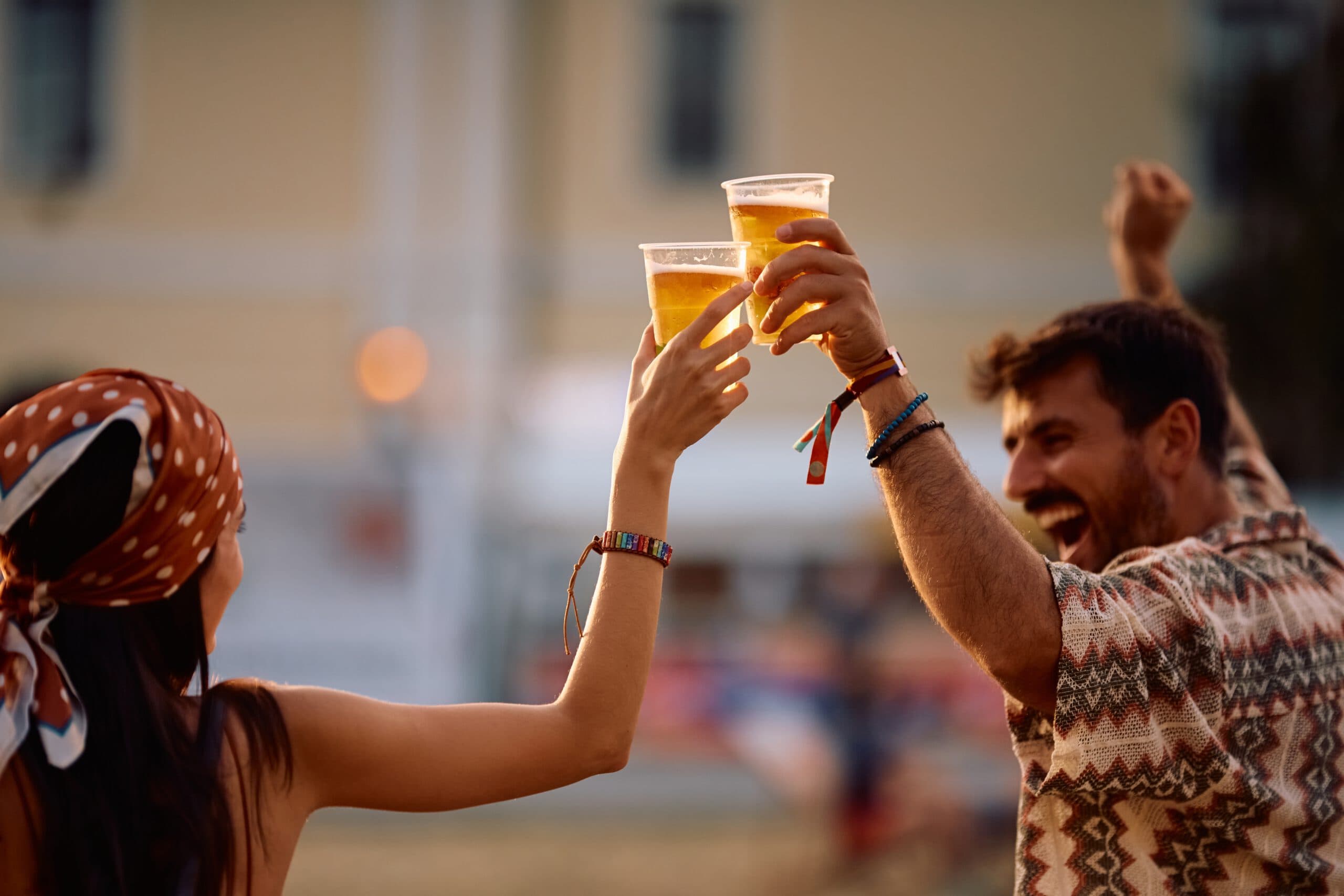 Close,Up,Of,Couple,Of,Festival,Goers,Drinking,Beer,And