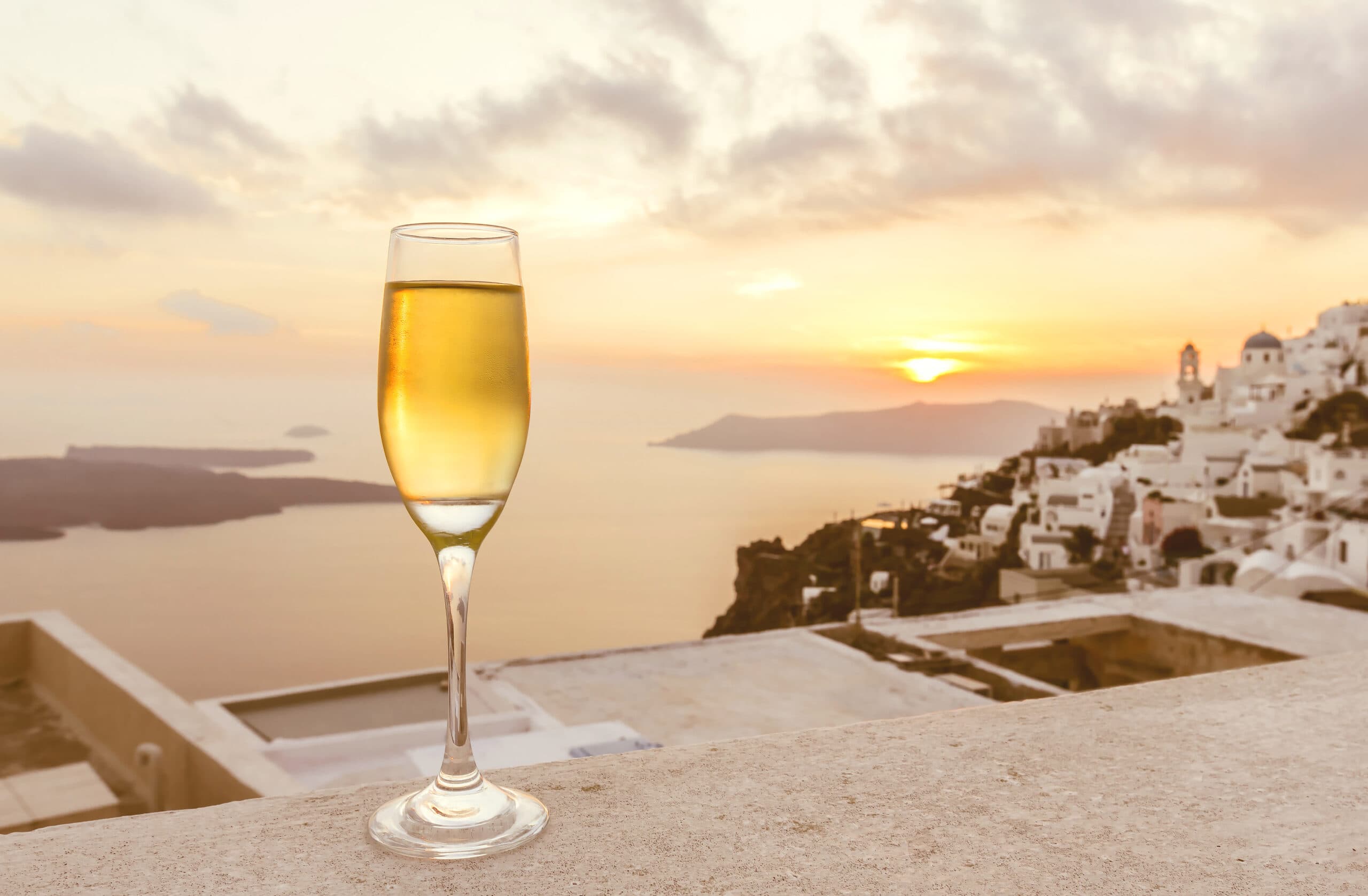 A,Glass,Of,White,Wine,On,Balcony,With,Caldera,City
