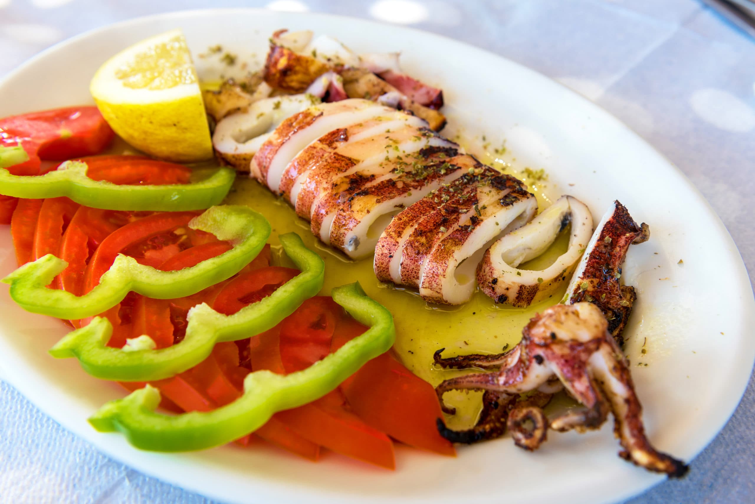 Seafood,,Grilled,Calamari,Served,With,Tomatoes,,Green,Peppers,And,Lemon.